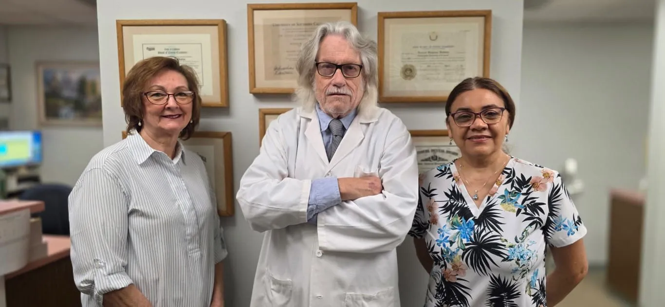 Dr. Richard Baldwin with two members of his dental team at his Huntington Beach practice, in front of framed dental credentials