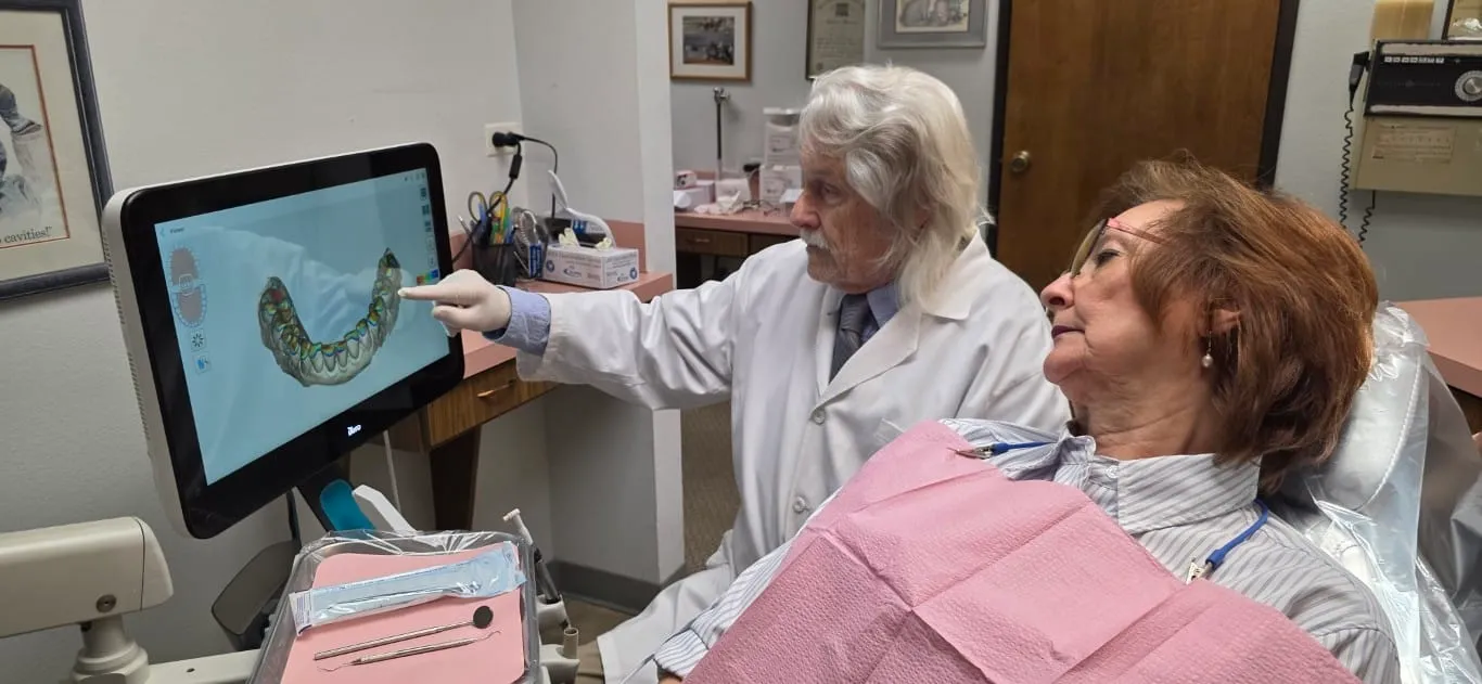 Dr. Richard Baldwin showing a patient a 3D scan of her teeth on a chairside iTero monitor at his Huntington Beach office