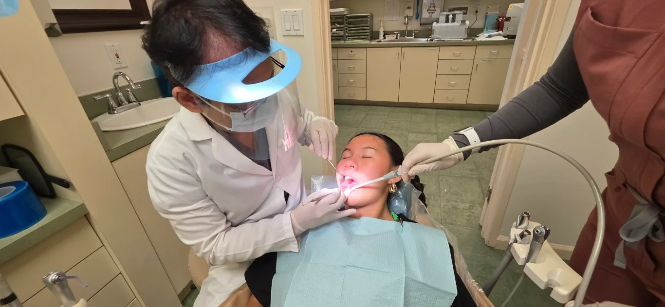 Dr. Kenneth Tran treating a patient with an assistant in a treatment room at Peninsula Dentistry & Orthodontics, Huntington Beach